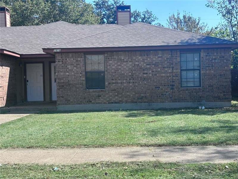 View of side of property featuring a lawn, a shingled roof, and brick siding