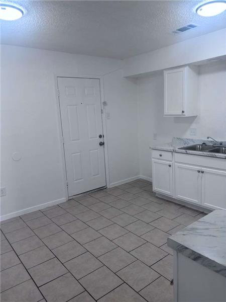 Kitchen with white cabinetry, a textured ceiling, light countertops, and light tile patterned floors