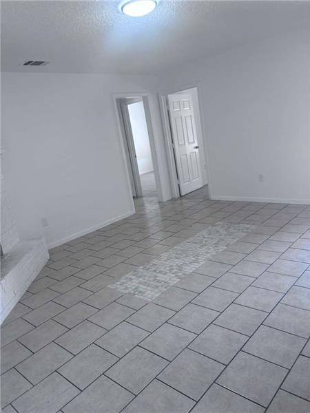 Spare room featuring a textured ceiling and light tile patterned flooring