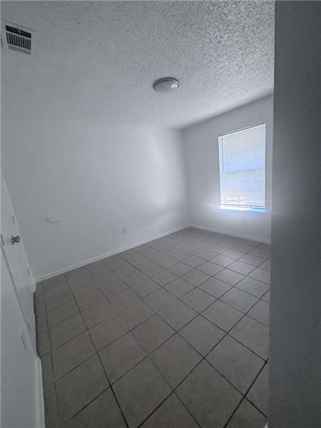 Spare room with a textured ceiling and tile patterned flooring