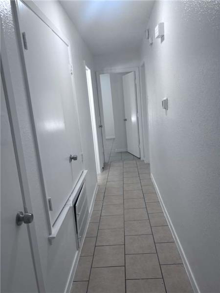 Corridor featuring light tile patterned floors and a textured wall