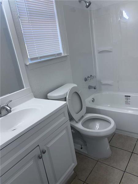 Full bathroom with bathing tub / shower combination, vanity, and light tile patterned floors