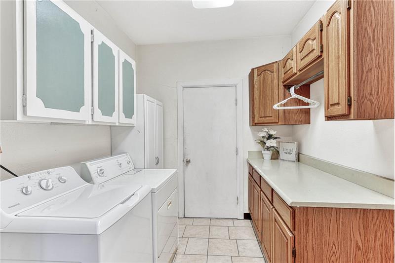 Laundry room with cabinets for storage, garage access, and washer/dryer that stays