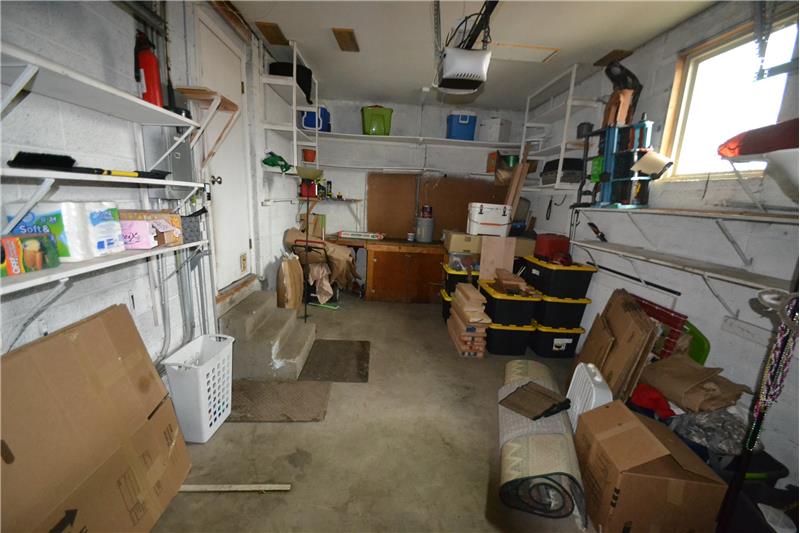 Extra long garage with natural light, workbench and lots of shelving on cinderblock walls