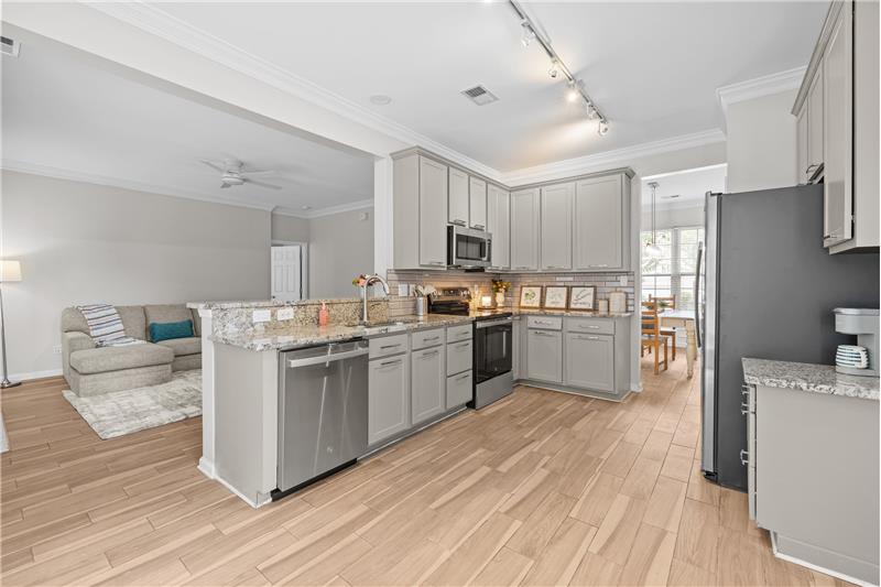 Freshly painted kitchen cabinets with new hardware, breakfast bar, open sight lines to living room