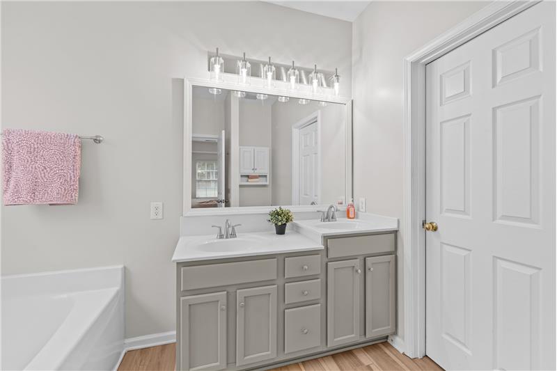 Primary bathroom features double-sink vanity, new light fixture, soaking tub