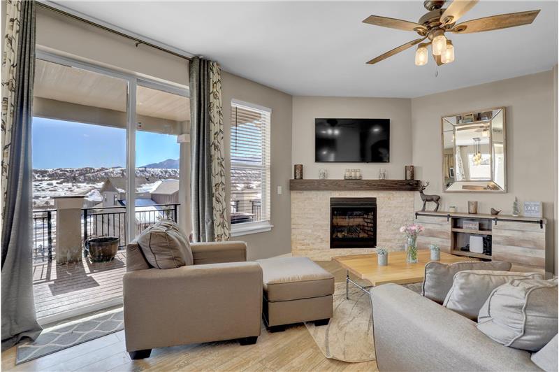 The Great Rm features a beautiful fireplace with a stacked stone surround and modern wood mantel & walkout to an expansive deck