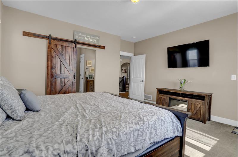 The Primary Bedroom offers a custom barn door leading to an adjoining luxurious bathroom