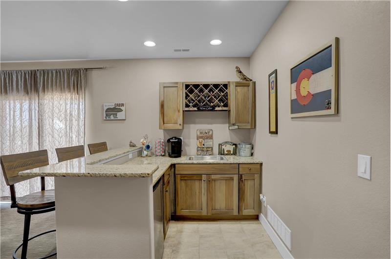 Basement wet bar that is perfect for entertaining with a counter bar, large sink, and fridge