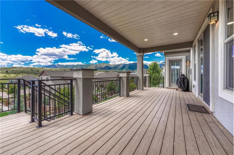 Covered composite deck with recessed lighting and iron rails to the backyard