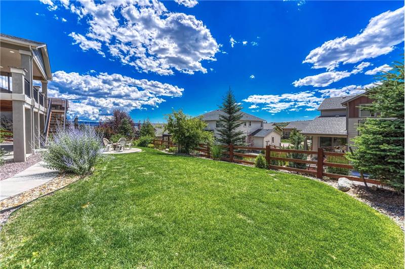 Beautifully manicured fenced backyard with trees and shrubs