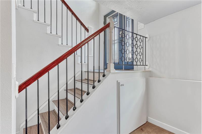 The stairs have iron rails to the upper and lower levels of the house