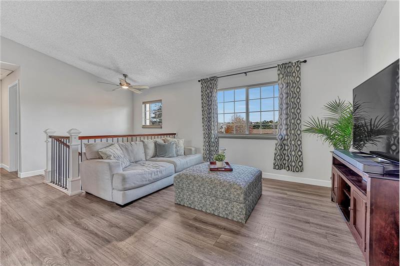 The vaulted Living Room has a lighted ceiling fan, a large window, and a pass-thru to the Kitchen