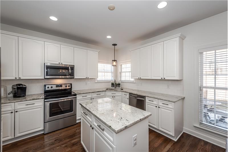 Renovated kitchen with white cabinets, granite counters, island, hardwood floors, stainless steel appliances.