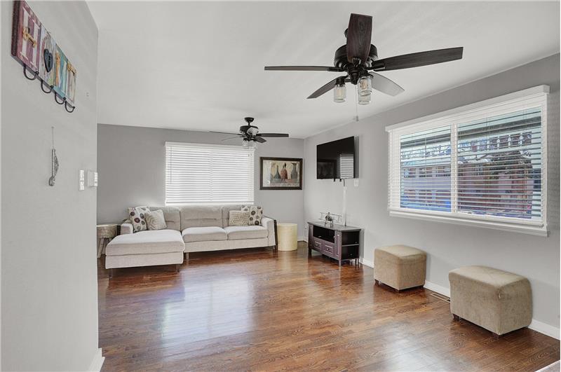 The Living Room features 2 lighted ceiling fans, hardwood floors, and large windows for abundant light