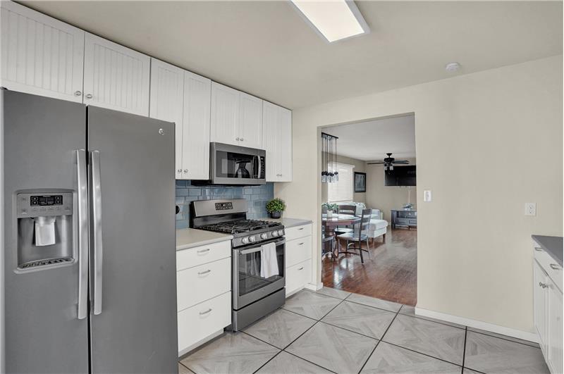 Kitchen appliances include a gas range oven, microwave, dishwasher, and side by side refrigerator