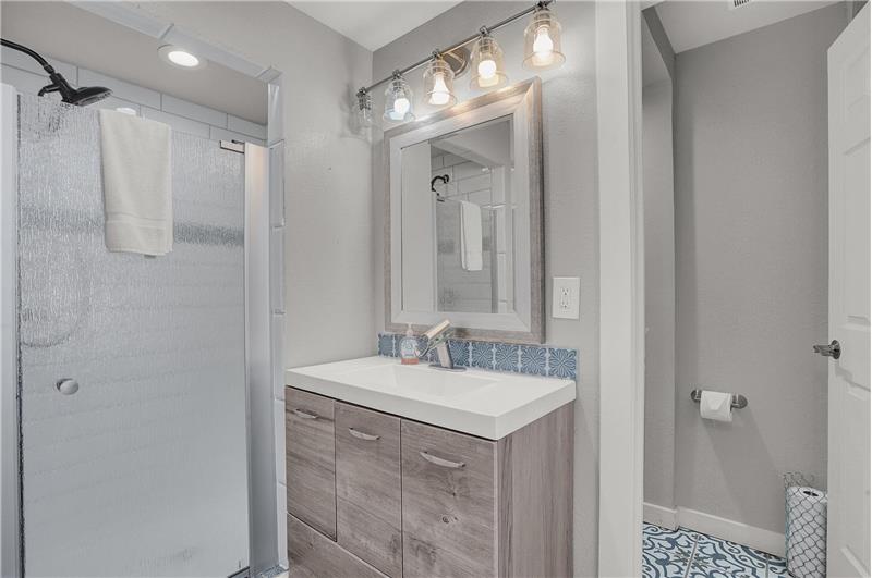 The Shower Bathroom features a vanity, framed mirror, and tiled shower