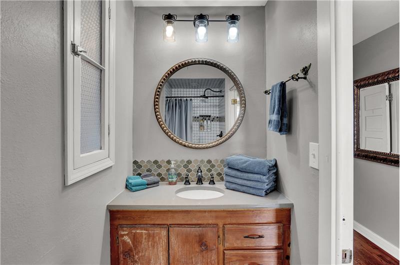 The upper level shower bathroom has a vanity, framed mirror, and updated lights