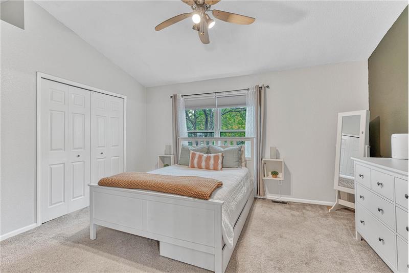 Primary bedroom with neutral carpet,, accent wall, and ceiling fan