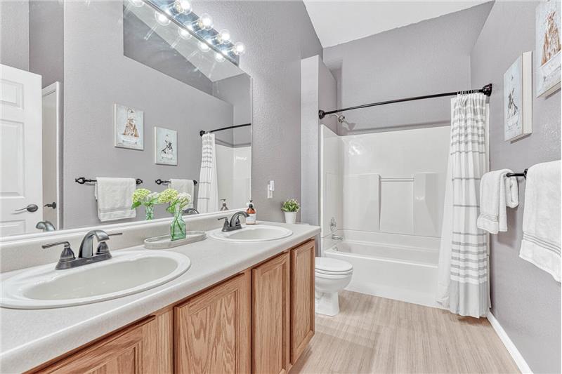 The Primary bathroom includes a luxury vinyl plank floor, a linen closet, dual sink vanity, skylight, & tub/shower