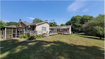 A grassy yard with mature trees, a multi-level wood deck.