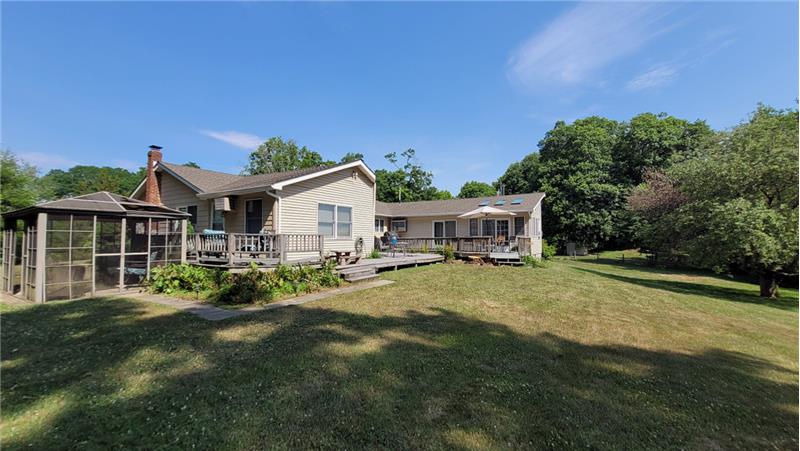 A grassy yard with mature trees, a multi-level wood deck.