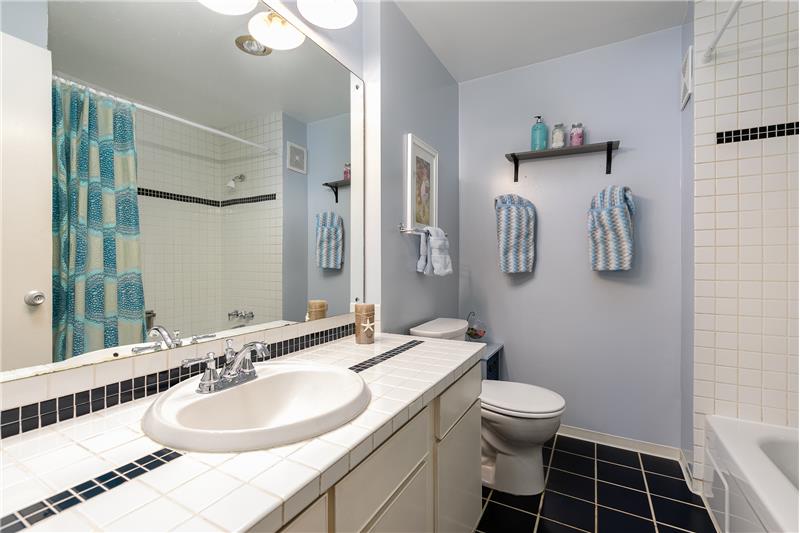 Full bath near 2nd bedroom with tile floor, tub surround and countertop.