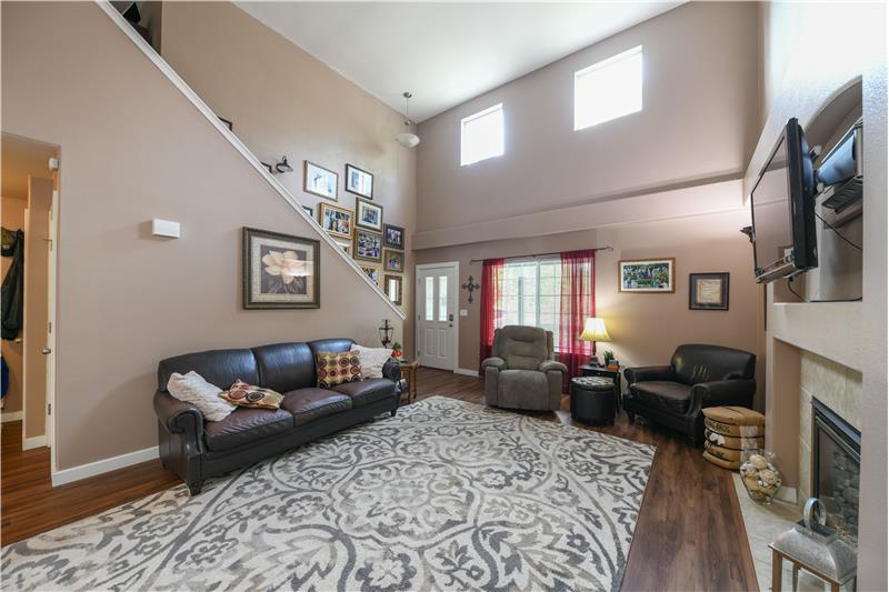 Angle of living room from dining area. Open staircase, transom windows, cathedral ceiling, and natural gas fireplace!
