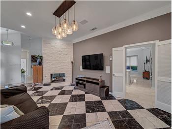 Living room featuring a stone see though fireplace, decorative marble floors and ornamental molding. Built in whole house SS