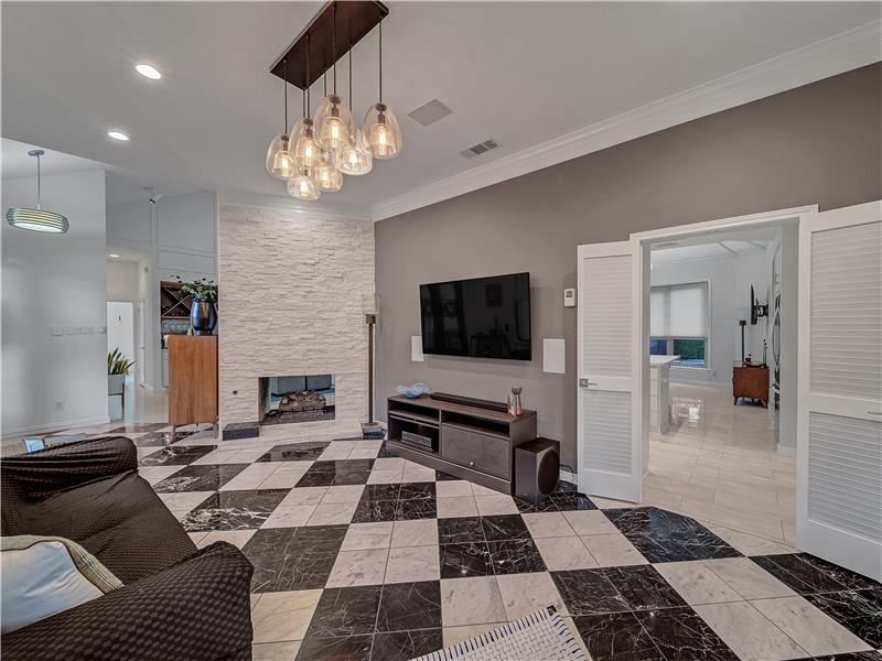 Living room featuring a stone see though fireplace, decorative marble floors and ornamental molding. Built in whole house SS