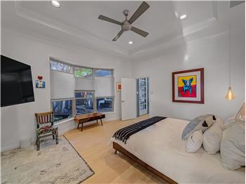 Primary Bedroom featuring a tray ceiling, crown molding, ceiling fan, and hardwood / wood-style flooring