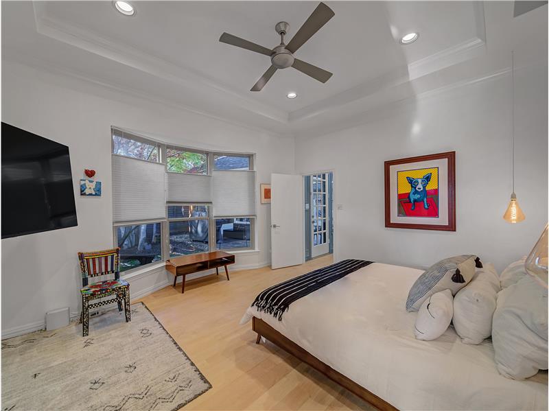 Primary Bedroom featuring a tray ceiling, crown molding, ceiling fan, and hardwood / wood-style flooring