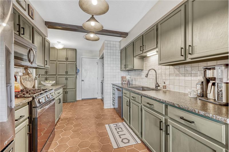 Updated kitchen with tile flooring, stainless steel appliances, tile backsplash, and granite counters