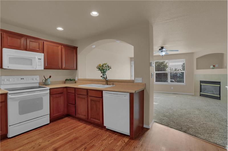 Functional kitchen with included appliances, recessed lighting, hardwood flooring, and cherry cabinets