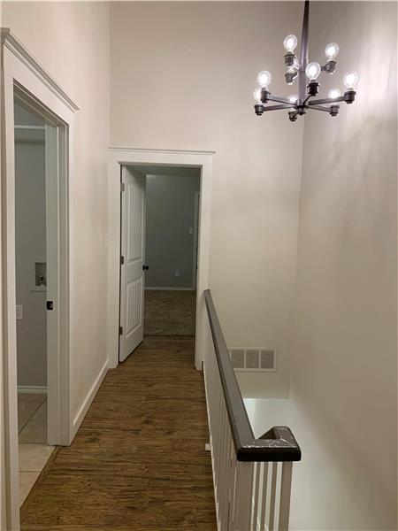 Hall featuring a chandelier, wood finished floors, and an upstairs landing