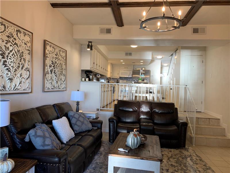 Living room featuring coffered ceiling, a chandelier, light tile patterned floors, beam ceiling, and stairs