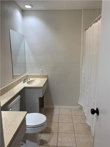 Master bath with vanity, a textured ceiling, tile patterned floors, and a shower with shower curtain