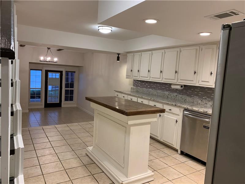 Kitchen with appliances with stainless steel finishes, light tile patterned floors, decorative backsplash, a chandelier, and a k
