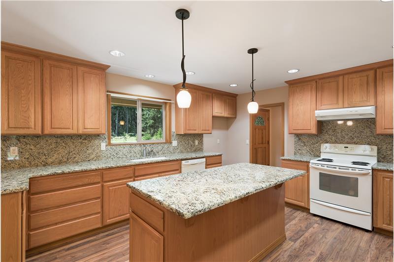 This spacious kitchen features granite countertops with lots of space for food prep and entertaining.