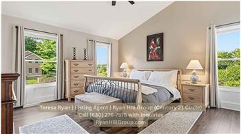 17-by-14-foot primary bedroom opens beneath a 12-foot shed-style ceiling. A custom ceiling fan, wainscoting, and multiple window