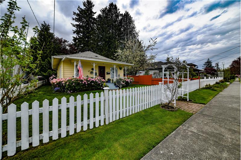 Sidewalk goes in front of the white picket fence and antique rose arbor. These antique roses typically bloom twice a year.
