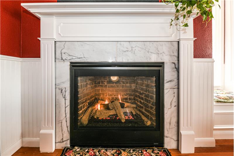 Living room fireplace with marble face and wood mantle.