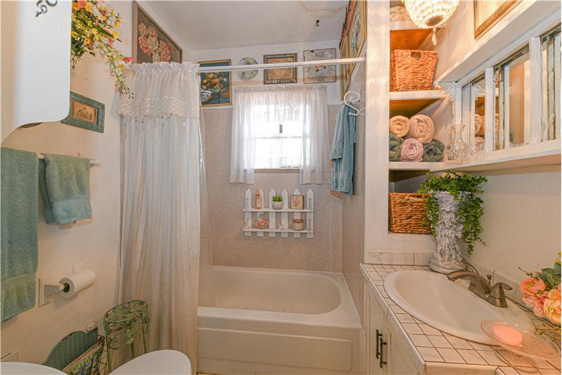 Another angle of bathroom as seen when you enter with built-in storage, full tub and new shower head.