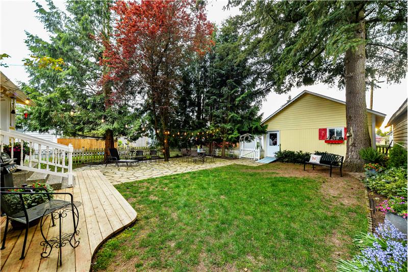 Another angle of backyard showing detached garage, back deck, and detached garage.
