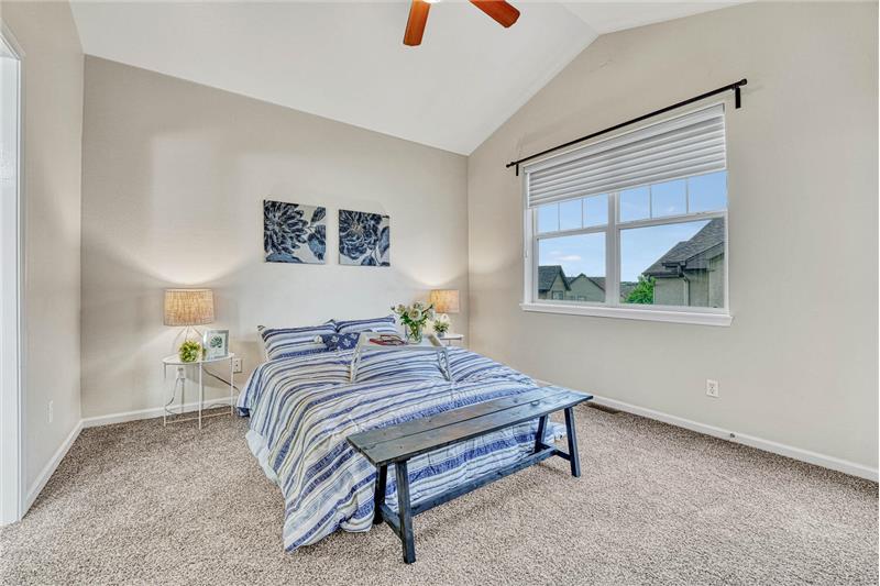 Primary bedroom with vaulted ceilings, ceiling fan, and adjoining 3/4 bath