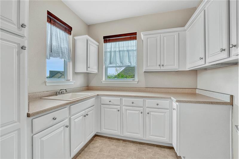 Functional laundry room w/ Pikes Peak views,that offers everything you need: storage, a sink, windows, and room to fold laundry!