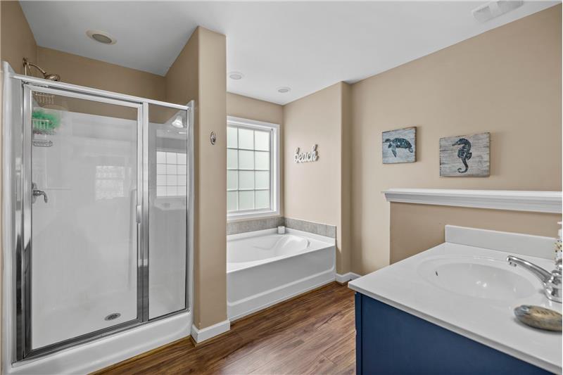 Owner's bathroom: soaking tub, luxury vinyl plank floor, separate shower.