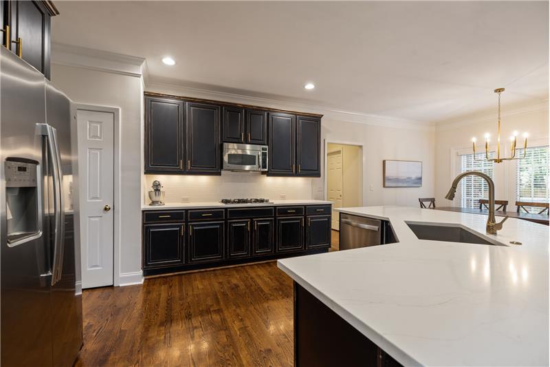 Under cabinet and recessed lights, expansive quartz counters, brushed brass fixtures, deep stainless sink