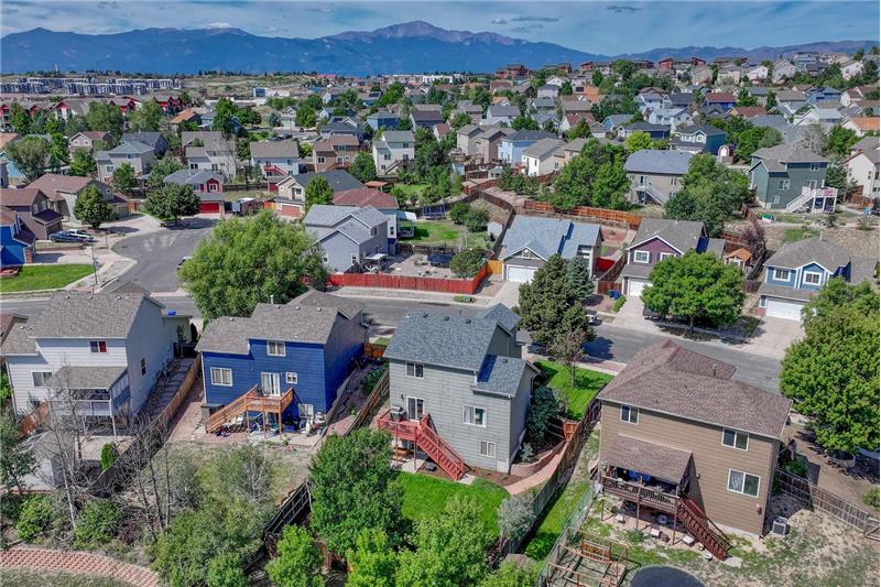 Aerial rear view of home, backyard, and neighborhood with mountain views in the front.