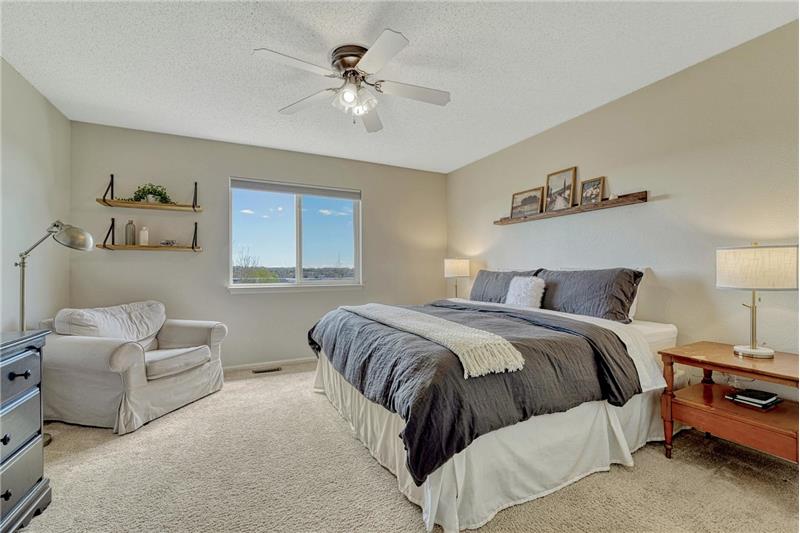 The UL Primary Suite features a ceiling fan, large window, walk-in closet, & en-suite bath with dual-sink vanity & tub/shower.